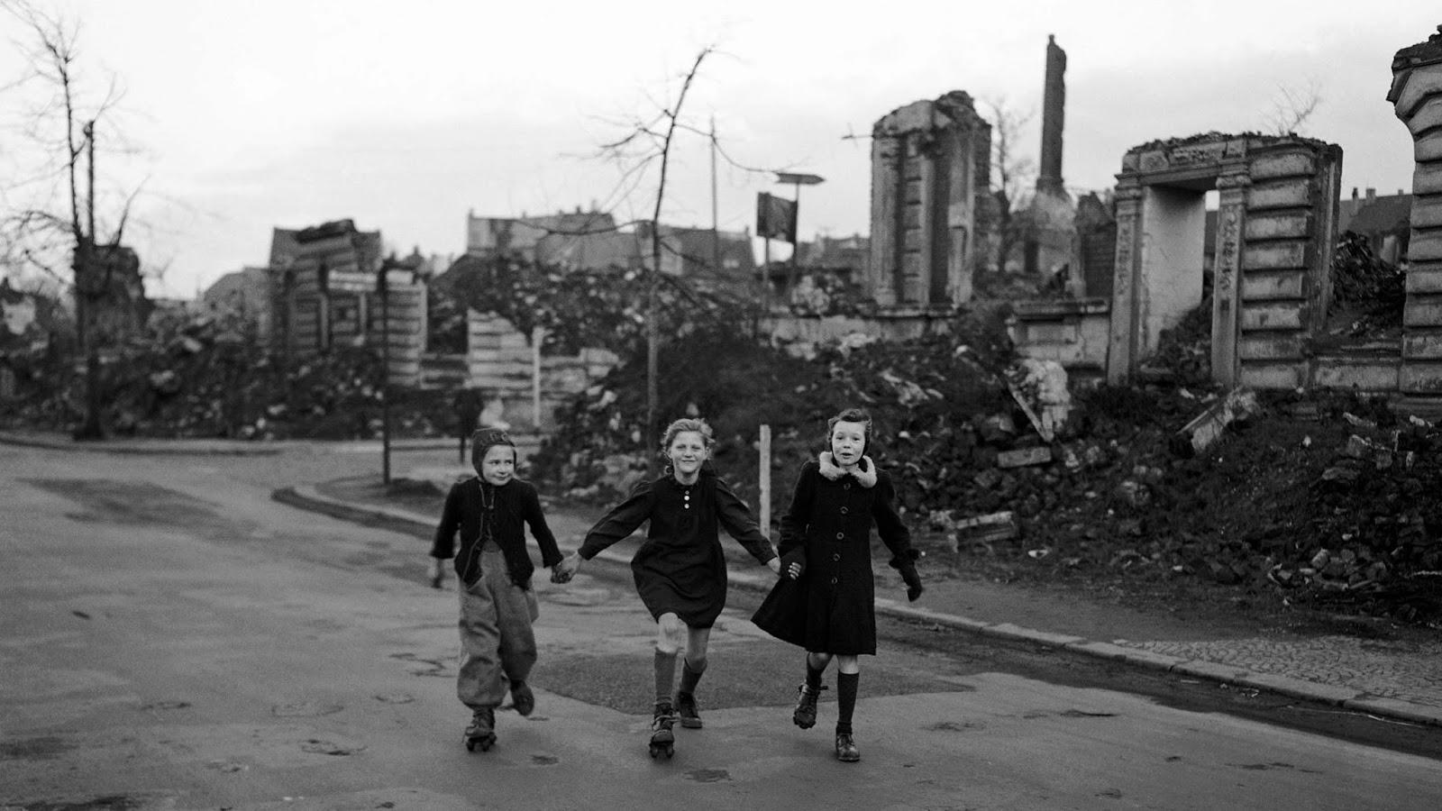 Trois collégiennes de patinage de la maison de l'école en passant blocs de maisons détruites à Essen, en 1949