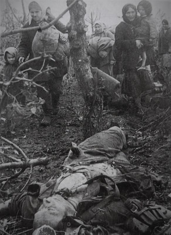Les soviétiques, les réfugiés de retour, passent devant le corps tué un soldat allemand