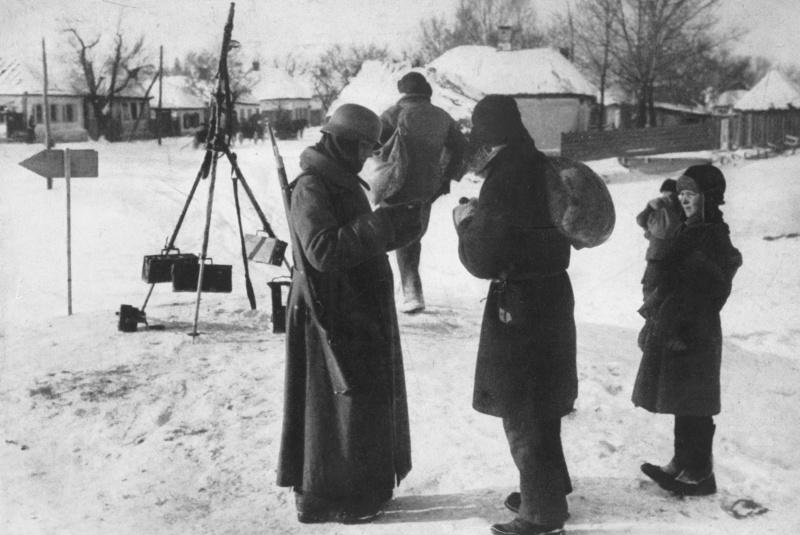 Le soldat allemand vérifie les documents de paix résident avant d'entrer dans le village soviétique